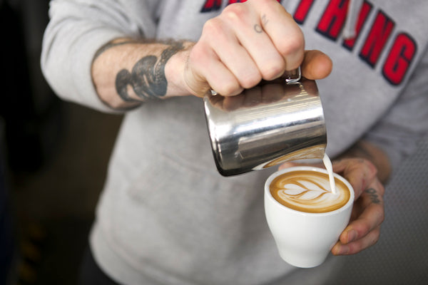 Sam James pours milk to create cappuccino latte art